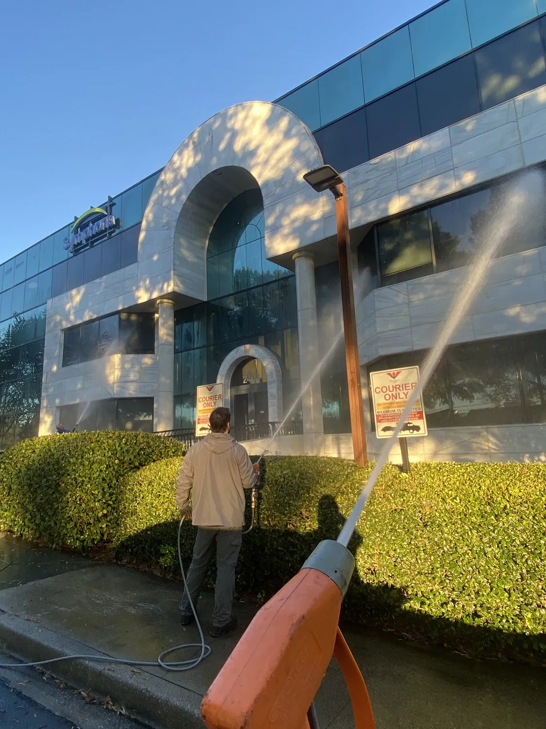 A crew member rinsing a mirrored glass office facade