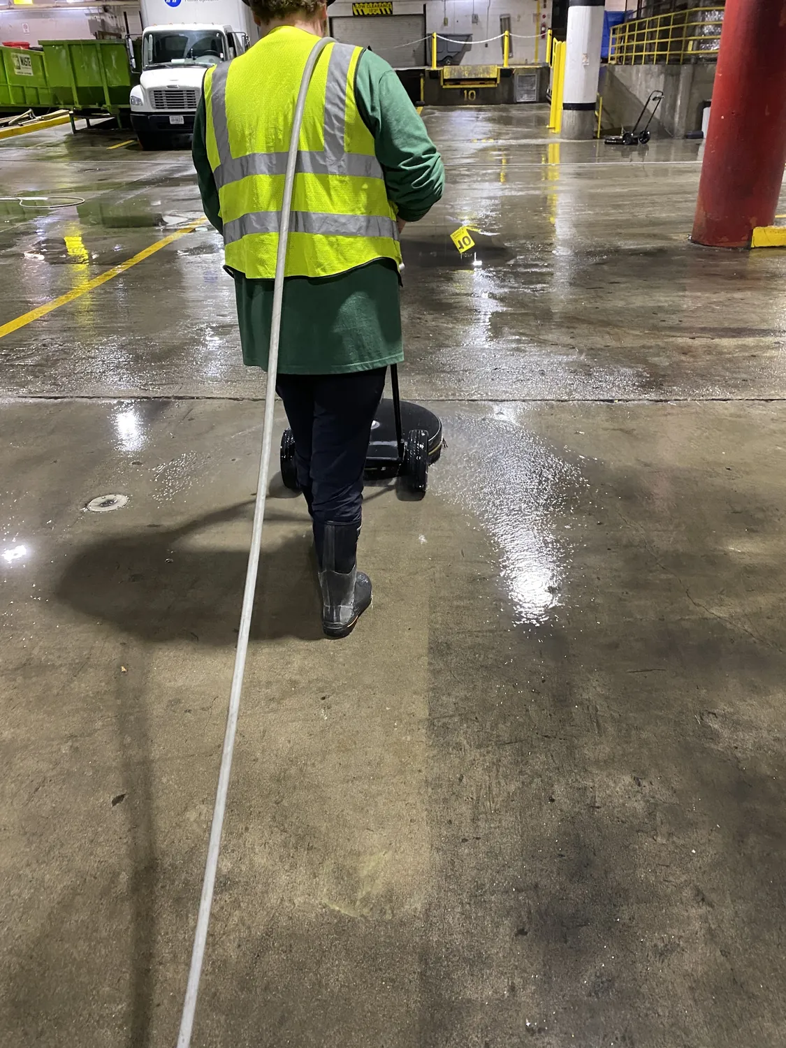 A crew member surface cleaning a parking garage floor